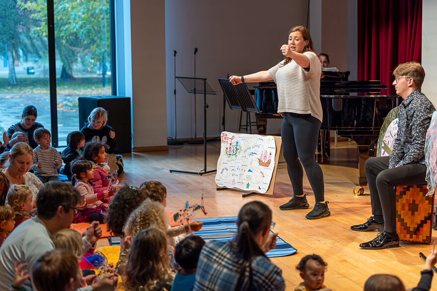 A woman stood in front of a group of parents and children sat on the floor