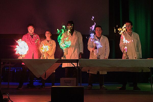 5 people in lab coats with different coloured flames in front of them 