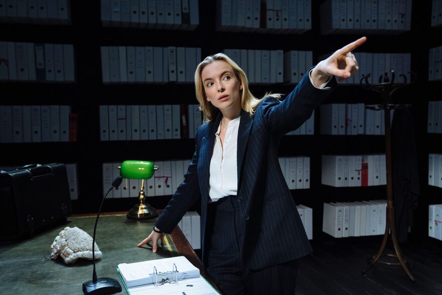 Jodie Comer as a barrister in her chambers pointing off stage. 