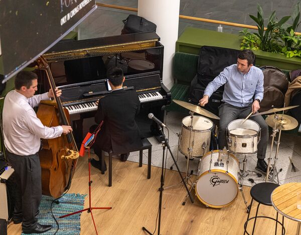 Jazz musicians play a cello, grand piano and drums.