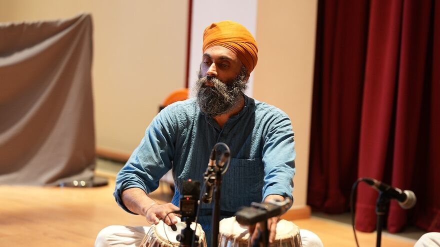 Man in orange turban playing drums.