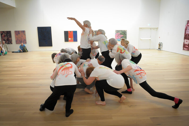Elders dance performers performing in Mead Gallery, positioned in a huddle