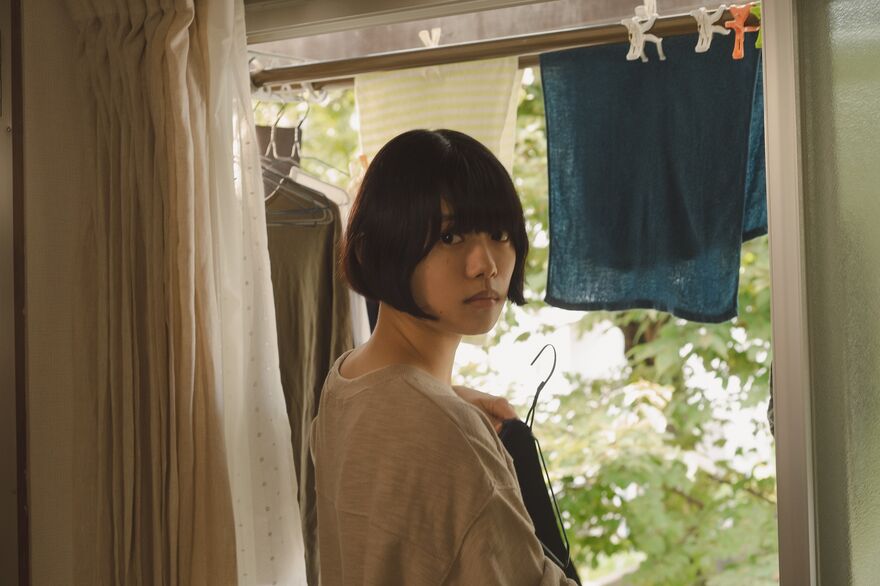 A woman looks over her shoulder as she hangs washing to dry. 