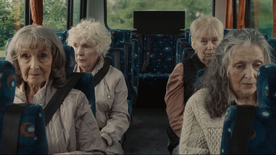 Four older women sit separately on a bus. 