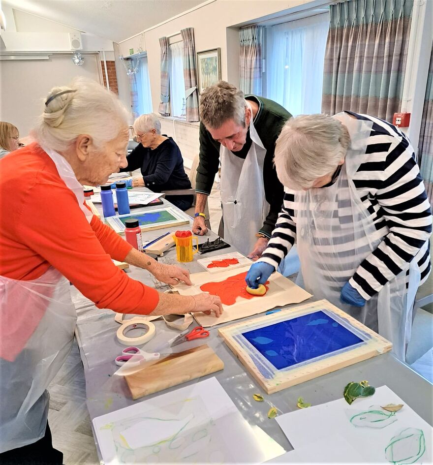 Senior care home residents screen printing at a table