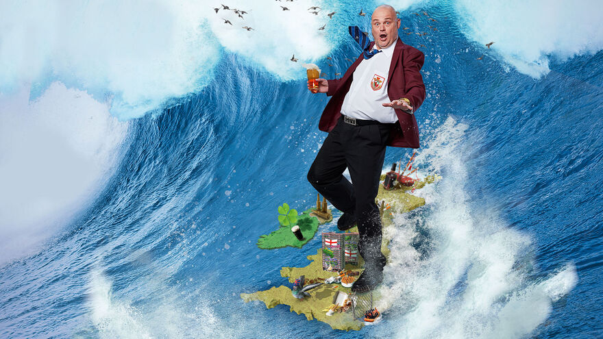 Al Murray holding a beer and surfing on the UK