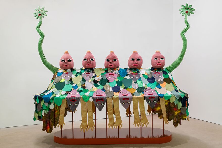 Sculpture of five figures with pink heads and yellow arms