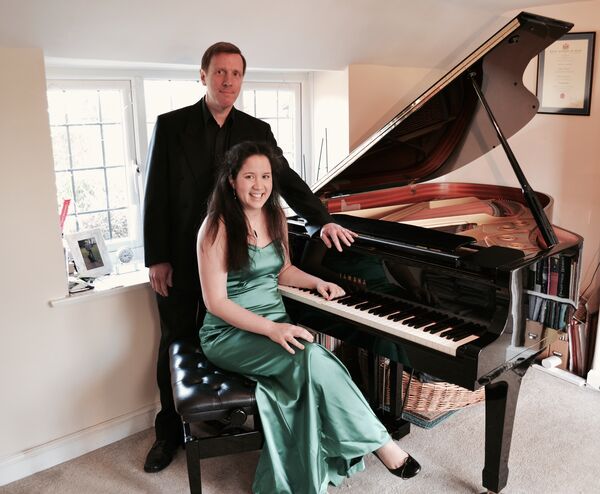 Woman and man sitting and standing at a grand piano