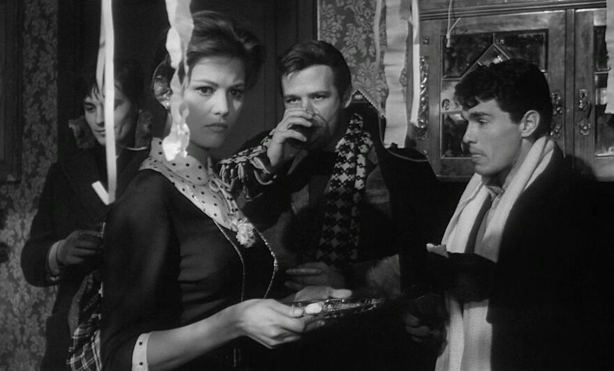 A black and white image of a woman standing together with three men at a party. 