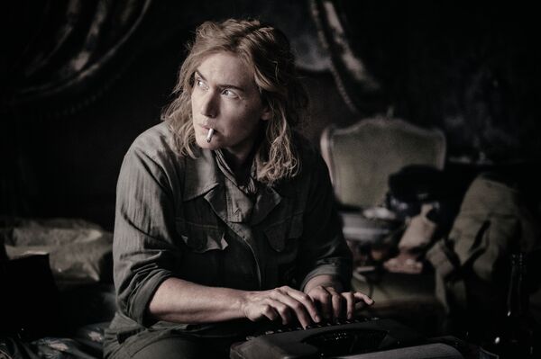 Kate Winslet as Lee Miller typing on a typewriter with a cigarette in her mouth. 